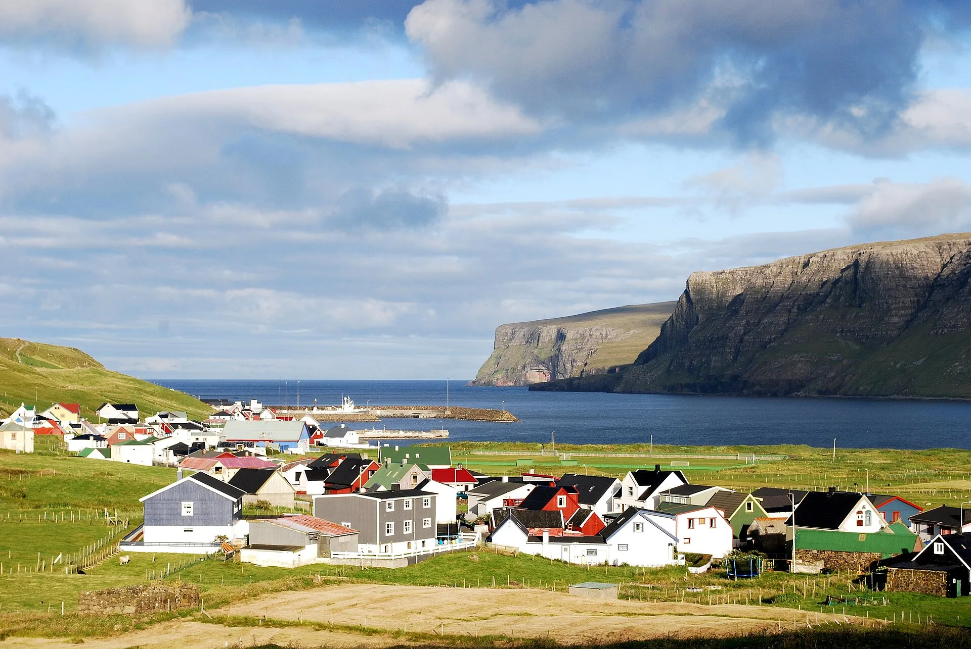Village de Suðuroy au bord d'un fjord, maisons colorées au pied de hautes pentes vertes