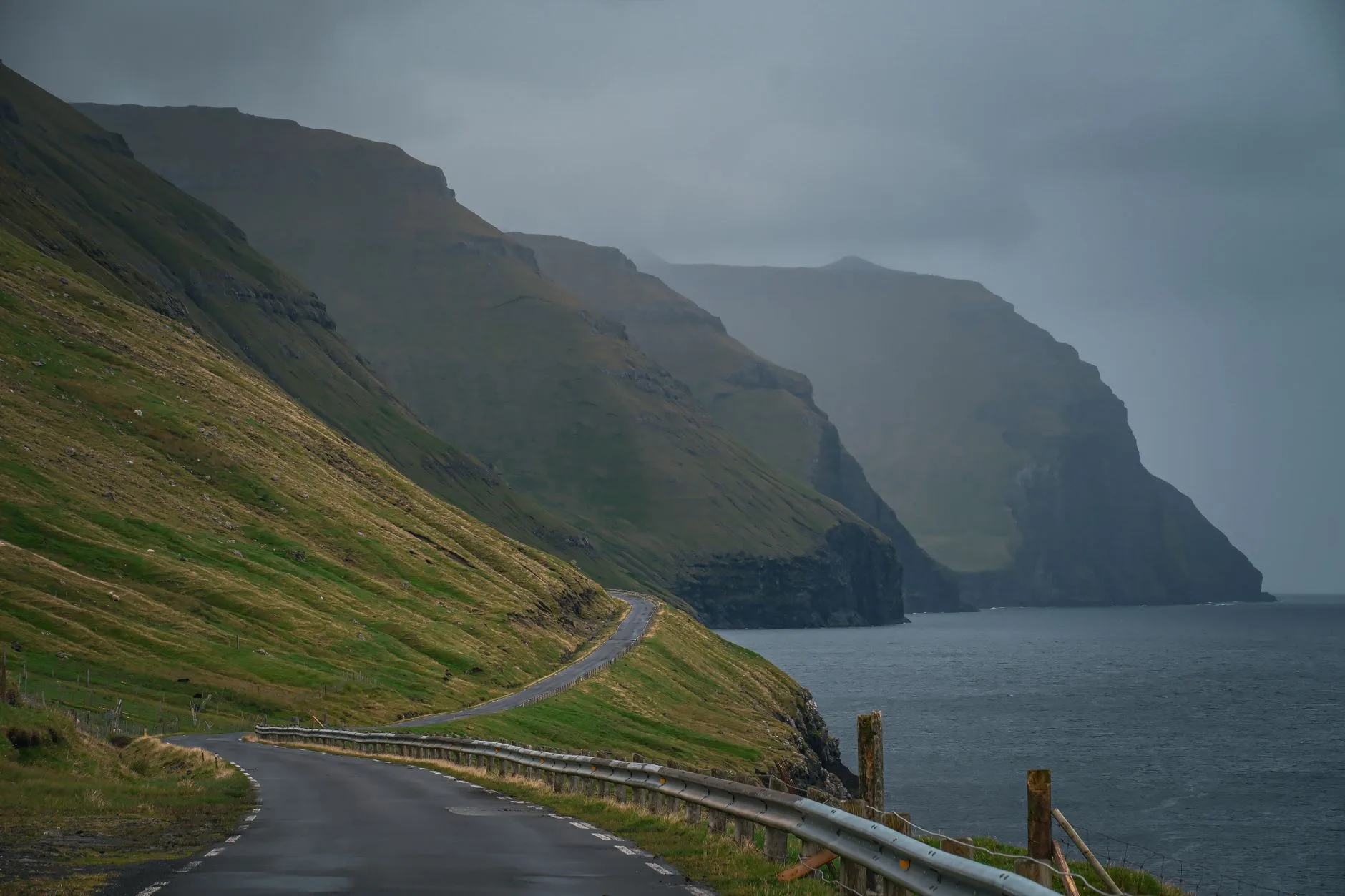 Route côtière et village aux toits d'herbe sur les îles Féroé